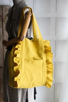 a woman holding a yellow handbag with ruffles on it