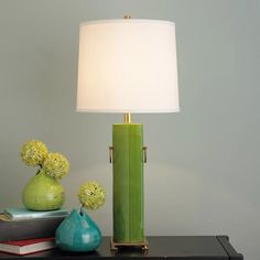 a green lamp sitting on top of a table next to a vase with flowers in it