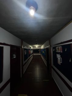 an empty hallway with several framed pictures on the wall and lights in the ceiling above