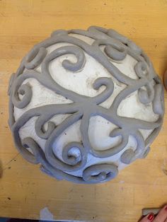 someone is working on an intricately designed object that looks like a ball ornament