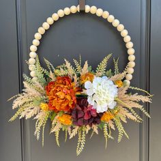 a wreath with flowers and beads hanging on a door