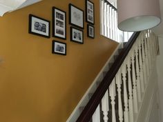 there are pictures on the wall next to the bannister and stair case in this house