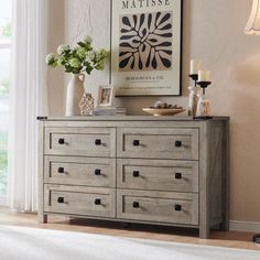 a dresser with many drawers and vases on it in front of a large window