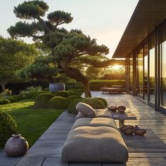 the sun is setting over an outdoor area with large couches and potted trees