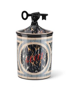 a black and white canister with an ornate design on the top, holding a metal hook