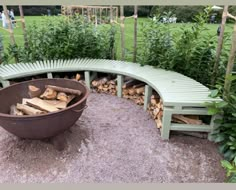 a circular bench made out of firewood in a garden with lots of green plants