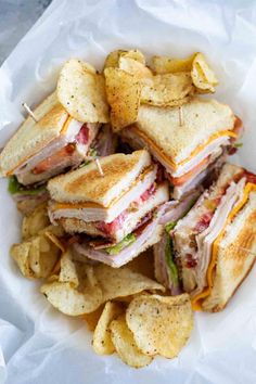 a sandwich cut in half with chips on the side and garnished with toothpicks