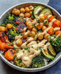 a bowl filled with broccoli, carrots and chickpeas covered in sauce