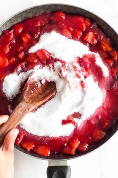 someone is stirring strawberries and sugar in a pot