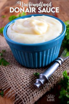 a blue bowl filled with cream sitting on top of a table next to parsley