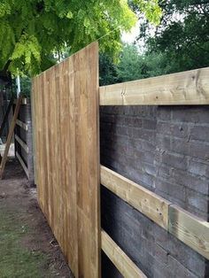 a wooden fence is next to a brick wall