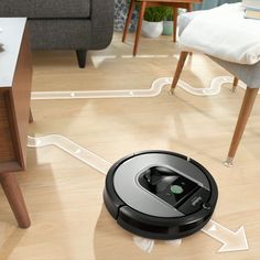 a roomba vacuum is on the floor in front of a table with a chair