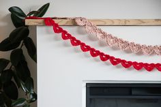 there are crocheted hearts hanging on the wall next to a fireplace mantel