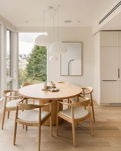 a dining room table with four chairs and a large window overlooking the trees in the background