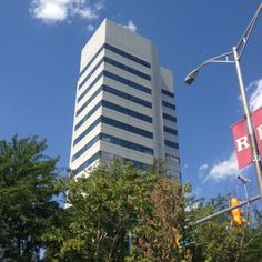 a tall building sitting next to a traffic light on a city street with trees in the foreground