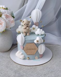 there is a small cake decorated with hot air balloons and a teddy bear on top