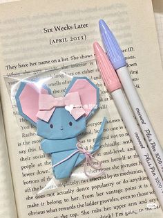 two pink and blue origami mice on top of an open book next to each other