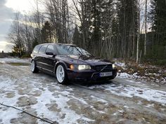 a purple car parked on the side of a road in front of some snow covered trees