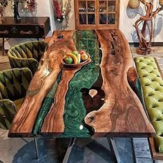 the table is made out of wood and has green velvet chairs around it, along with a bowl of fruit