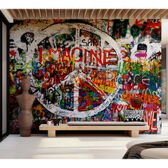 there is a large wall with graffiti all over it and a bench in the foreground