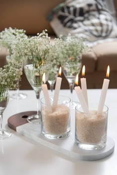 candles are lit in small glass vases on a tray