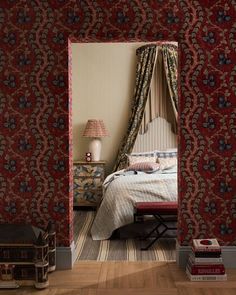 a bedroom with red and blue wallpaper, wooden flooring and a canopy bed