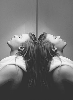 two women are laying on the floor in front of a mirror looking at their hair