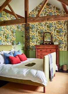 a bed sitting in a bedroom next to a wooden dresser and wallpaper covered walls