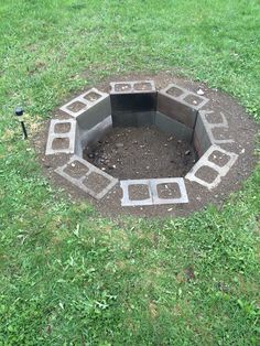 an open fire pit in the middle of some grass