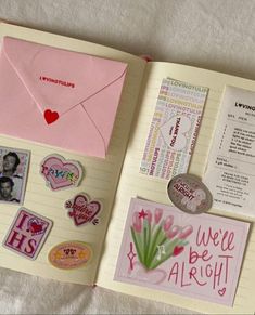 an open book with stickers and magnets on the pages, including a pink envelope