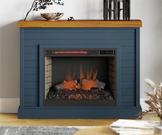 a blue fireplace with logs in it and a vase on top of the fire place