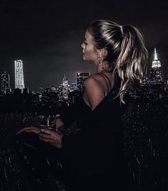 a woman standing in front of a city skyline at night