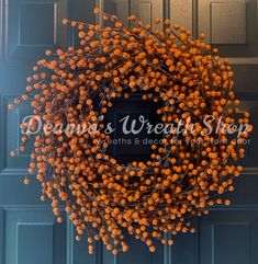 an orange berry wreath hangs on the front door