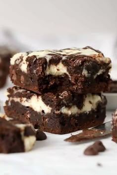 three chocolate brownies stacked on top of each other with white frosting and chocolate chips