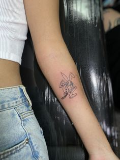 a woman's arm with a tattoo on it that has a cartoon character drawn on it