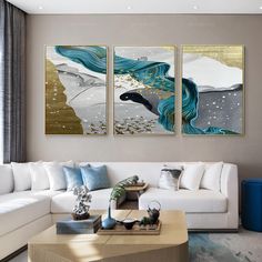 three paintings on the wall above a couch in a living room with white furniture and blue accents