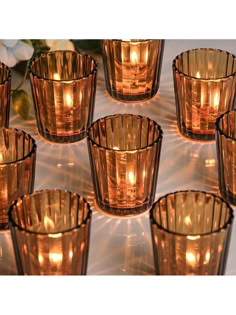 many lit candles are arranged in rows on a table