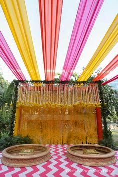 an outdoor ceremony with bright colored draping and gold rings hanging from the ceiling