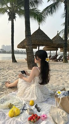 a woman sitting on top of a sandy beach next to palm trees and other items