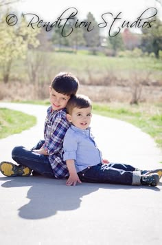 two young boys sitting on the ground with their arms around each other