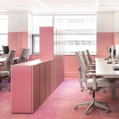 an office with pink walls and white desks