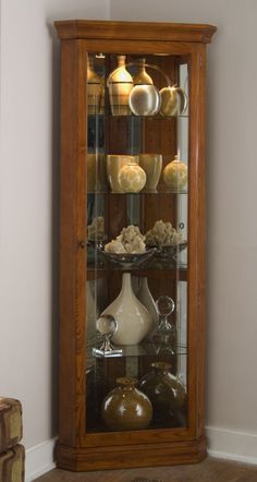 a display case with glass doors in the corner next to a vase and other items