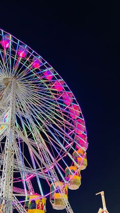 the ferris wheel is brightly lit up at night