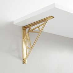 a gold metal shelf bracket on a white wall