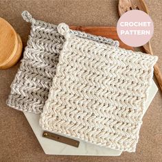 two crocheted dishcloths sitting on top of a white plate next to a wooden spoon