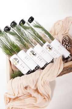 six bottles of wine sitting on top of a wooden box filled with pine cones and evergreen needles