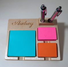 three different colored sticky notes on a wooden holder