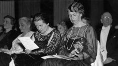 an old black and white photo of people sitting in chairs looking at something on paper