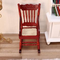 a miniature red rocking chair next to a book shelf