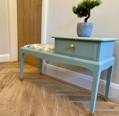 a blue table with a plant on top and a cushion under the foot rest in front of it